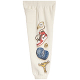 Off-white sweatpants featuring a vertical graphic print of various fashion items, including a red and white sneaker, a gold watch, a blue baseball cap, and a gold cross.