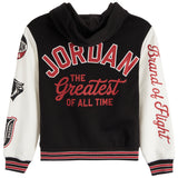 A black and white varsity-style hooded sweatshirt featuring 'JORDAN THE Greatest of All Time' printed in red on the front, with 'Brand of Flight' written vertically in red on the right sleeve and additional patches on the left sleeve.