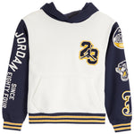 A Jordan brand hooded sweatshirt for kids, featuring an off-white body, navy blue sleeves and hood, with gold and white graphic details including 'JORDAN EIGHTY-FOUR' on the sleeve and a '23' patch on the chest.