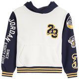 A Jordan brand hooded sweatshirt for kids, featuring an off-white body, navy blue sleeves and hood, with gold and white graphic details including 'JORDAN EIGHTY-FOUR' on the sleeve and a '23' patch on the chest.