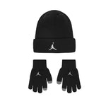 A black knit beanie and matching gloves set, both featuring a white embroidered Jumpman logo on the cuff and finger area, with gray tips on the gloves, shown on a plain white background.