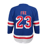 The back of a blue hockey jersey with 'FOX' and the number '23' in red and white, featuring red and white stripes on the sleeves and hem, shown on a plain white background.