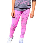 Pink leggings with a white speckled pattern and black heart, star, and flower drawings, worn by a child with a gray t-shirt and white sneakers against a white background.