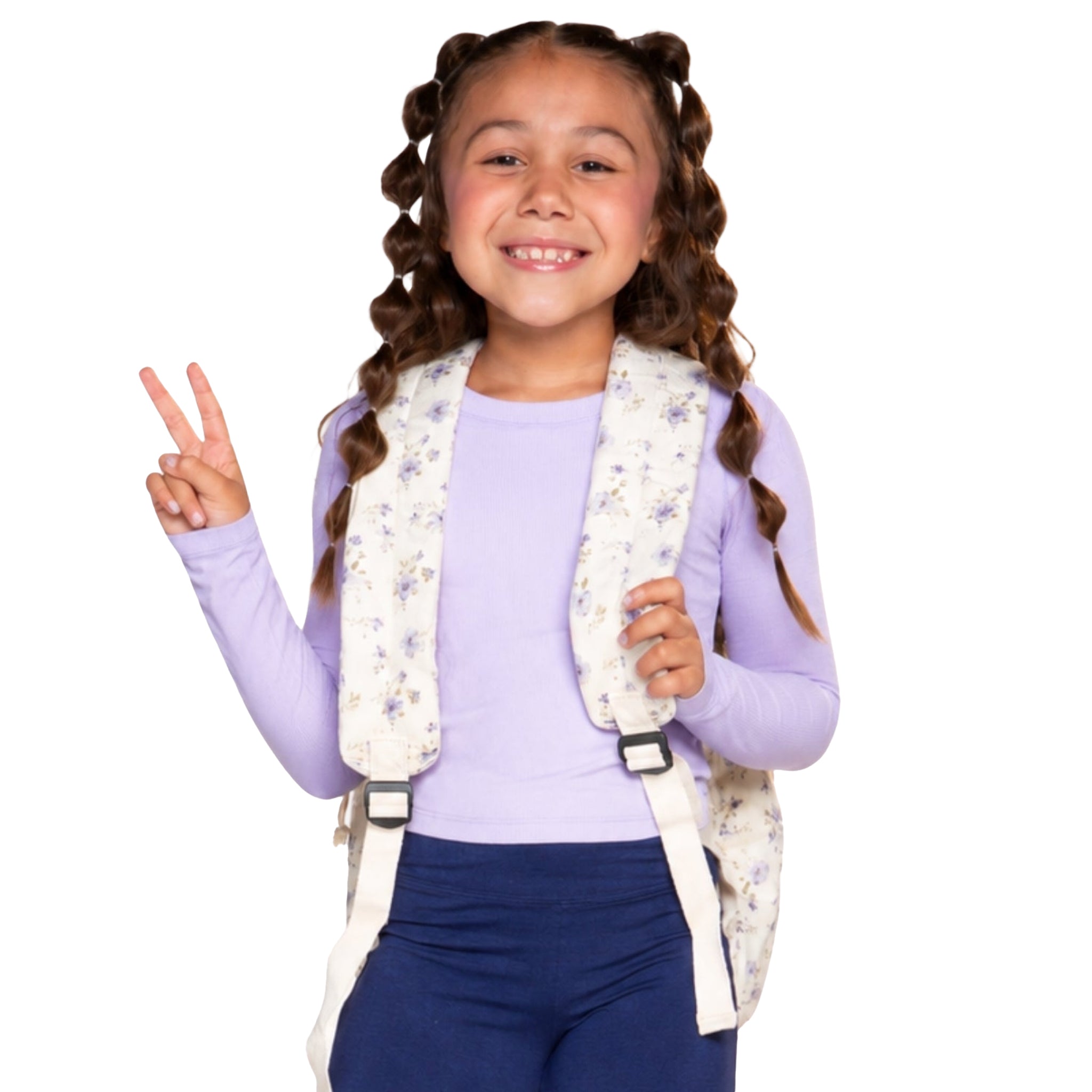 A young girl with bubble braided hair, smiling, and makes a peace sign while wearing a floral-patterned backpack over a light purple long-sleeve shirt and navy pants, set against a solid white background.