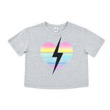 A light heather gray short-sleeve crop top t-shirt featuring a retro striped heart graphic in pink, yellow, and blue with a bold black lightning bolt running through the center.