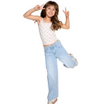 A young girl posing in a white spaghetti-strap crop top with a pink floral pattern and light-wash wide-leg jeans, making peace signs against a solid white background.