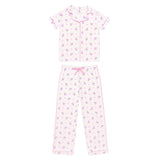A two-piece girls' pajama set featuring a short-sleeve button-front top and matching pants, both in a white fabric with a small purple floral print and pink piping details.