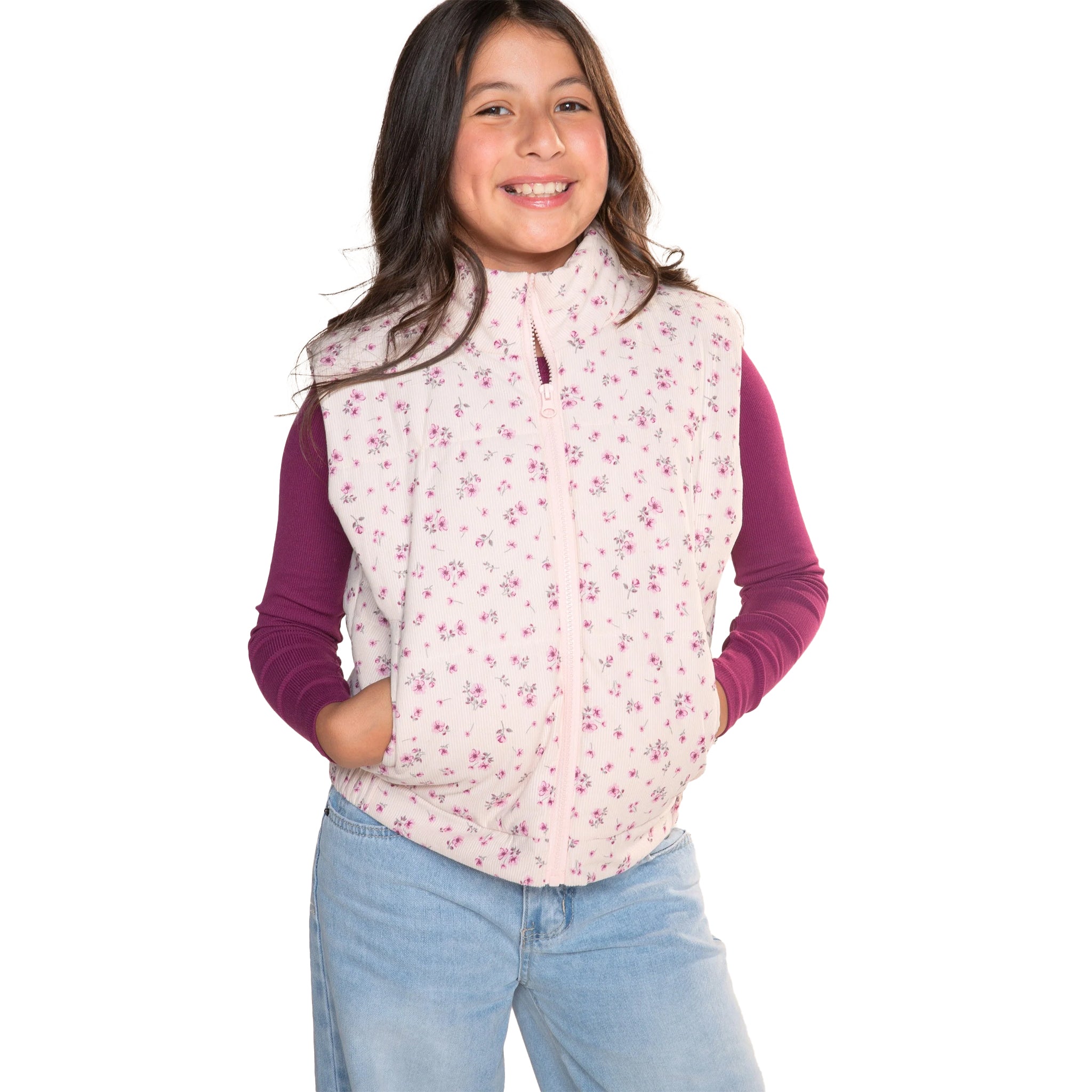 A young girl smiling and wearing a light pink zippered fleece vest with a small purple floral pattern, layered over a dark purple long-sleeve shirt and paired with light blue jeans, set against a plain white background.