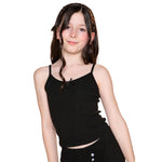A young girl with long dark brown hair wearing a black ribbed spaghetti-strap crop top and matching black bottoms, photographed against a solid white background.