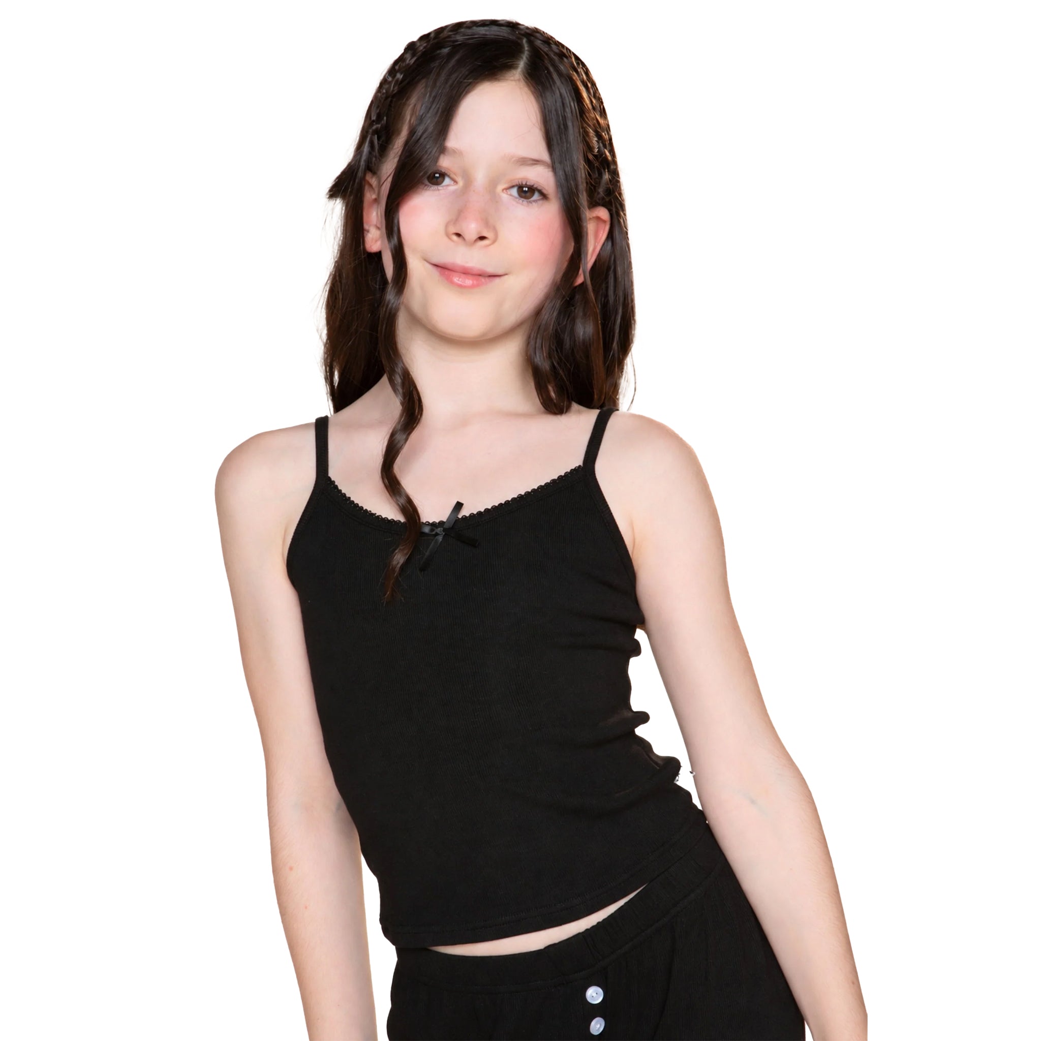 A young girl with long dark brown hair wearing a black ribbed spaghetti-strap crop top and matching black bottoms, photographed against a solid white background.