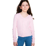 A young girl with long brown hair wearing a light pink long-sleeve button-up cardigan and blue jeans, standing against a solid white background.