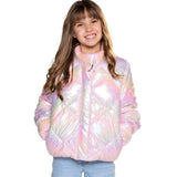 A young girl with long brown hair smiling while wearing a shiny, quilted puffer jacket with an iridescent pastel pink, purple, and blue sheen, paired with light blue jeans, against a solid white background.