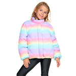 A young girl wearing a pastel rainbow striped quilted puffer jacket with a mock neck, paired with black leggings, against a solid white background.