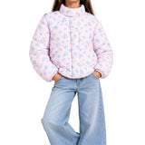 A child wearing a light pink quilted puffer jacket with a blue floral pattern, paired with light blue jeans, shown against a plain white background.