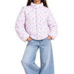 A child wearing a light pink quilted puffer jacket with a blue floral pattern, paired with light blue jeans, shown against a plain white background.