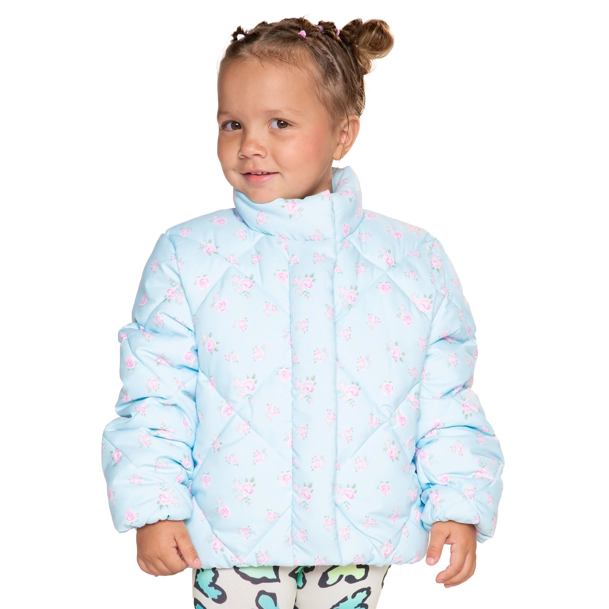 A young girl with her hair in two buns wearing a light blue quilted puffer jacket with a pink floral pattern, photographed against a solid white background.
