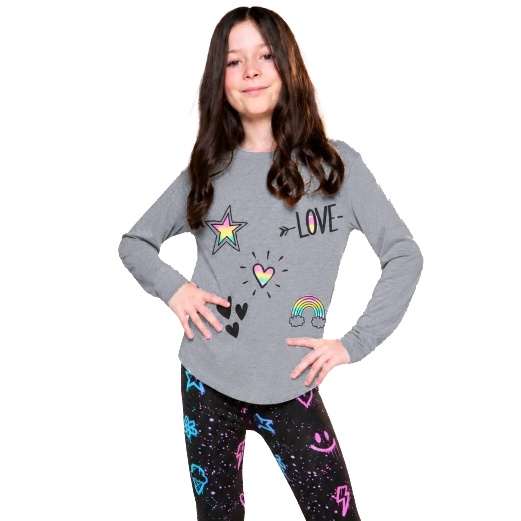 A young girl with long brown hair stands against a white background wearing a heather gray long-sleeve shirt with colorful graphic prints (star, heart, rainbow, 'LOVE' text) and black leggings with a colorful pattern.