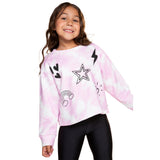 A young girl smiling and wearing a pink and white tie-dye long-sleeve sweatshirt with black graphic prints of a star, lightning bolt, hearts, and a rainbow, paired with black leggings, against a solid white background.