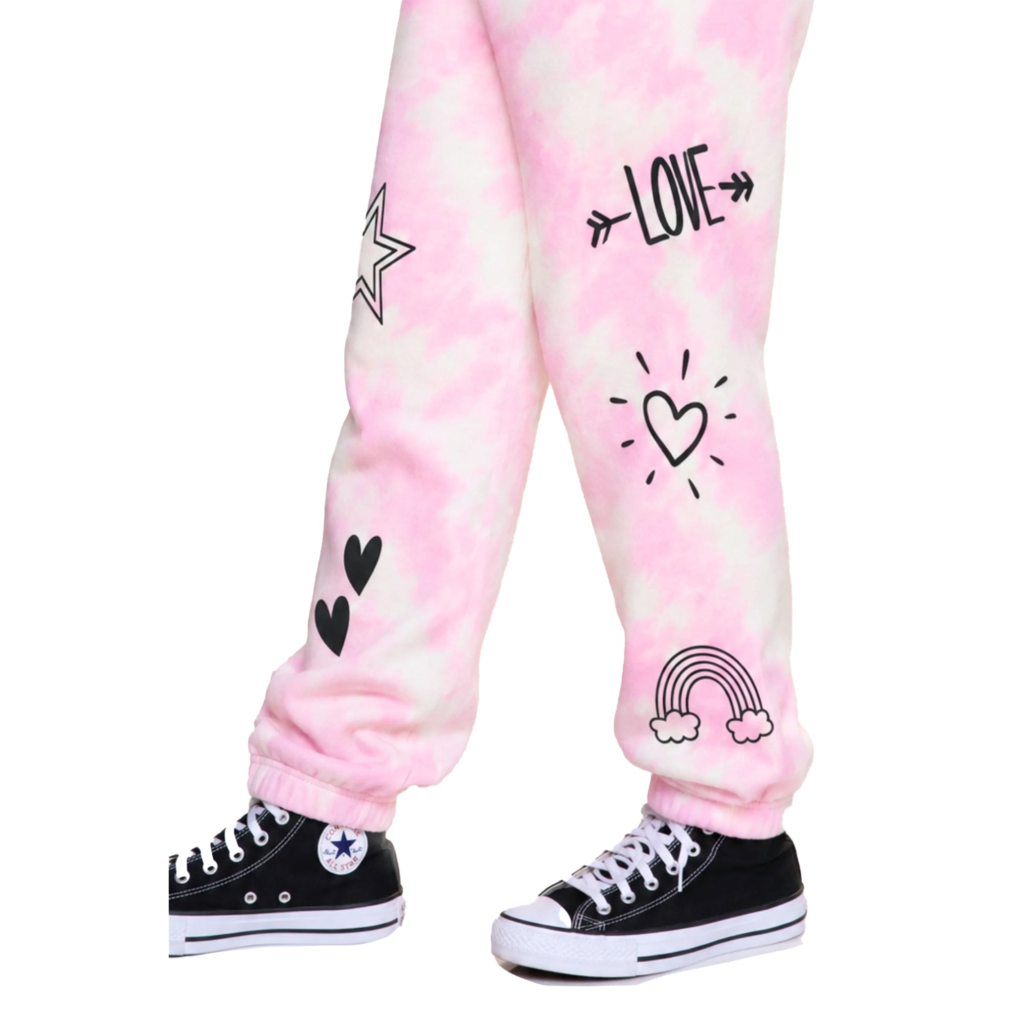 Pink and white tie-dye jogger pants with black graphic prints including hearts, a rainbow, a star, and the word 'LOVE' with arrows, shown on a child's legs with black Converse sneakers against a white background.