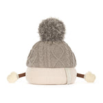 A gray cable-knit beanie hat on marshall figure with a fluffy gray pom-pom on top, a cream ribbed brim, and small cream pom-poms on the sides, photographed on a white background.