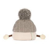 A gray cable-knit beanie hat on marshall figure with a fluffy gray pom-pom on top, a cream ribbed brim, and small cream pom-poms on the sides, photographed on a white background.