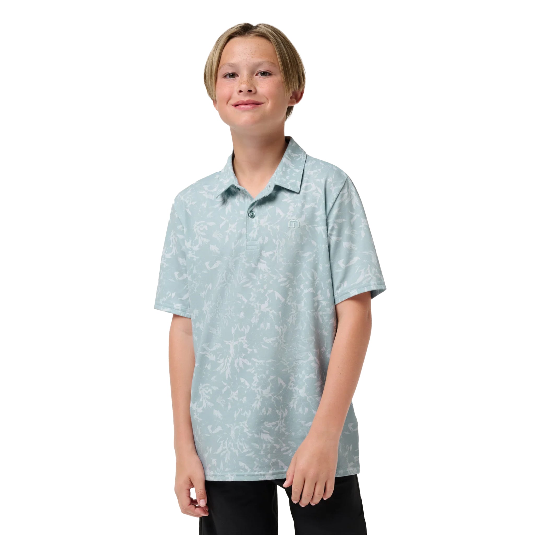 A young boy modeling a light blue short-sleeve polo shirt with a white abstract pattern, set against a plain white background.