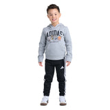 A young boy modeling a gray Adidas hoodie with a cartoon graphic and black Adidas track pants with white stripes, set against a plain white background.