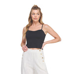 A woman modeling a black spaghetti-strap crop top paired with white pinstriped pants, set against a solid white background.