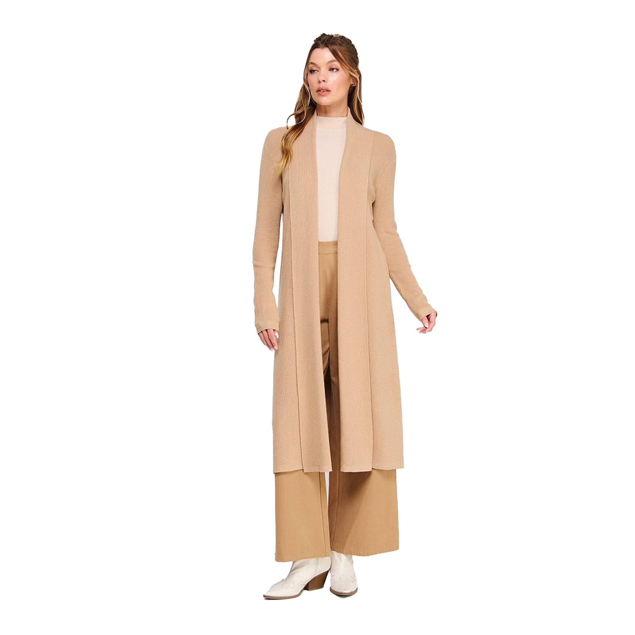 A woman modeling a long, open-front duster cardigan in a light tan/beige color, worn over a cream mock-neck top, matching wide-leg trousers, and white ankle boots, set against a plain white background.