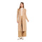 A woman modeling a long, open-front duster cardigan in a light tan/beige color, worn over a cream mock-neck top, matching wide-leg trousers, and white ankle boots, set against a plain white background.