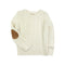 An off-white cable-knit sweater with a brown suede elbow patch, displayed flat against a solid white background.