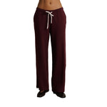 A person wearing burgundy wide-leg sweatpants with a white drawstring, shown from the waist down against a plain white background.