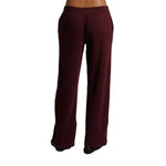 A pair of wide-leg sweatpants in a deep burgundy color, shown from the back on a model against a plain white background.