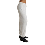A side profile view of a person wearing light heather gray knit jogger sweatpants with a drawstring waist and black loafers, shown against a plain white background.