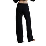 Black wide-leg pants shown from the back on a model, featuring a simple elastic waistband and straight, relaxed legs.