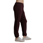 A person shown from the waist down wearing dark burgundy jogger sweatpants and white sneakers, photographed against a plain white background.