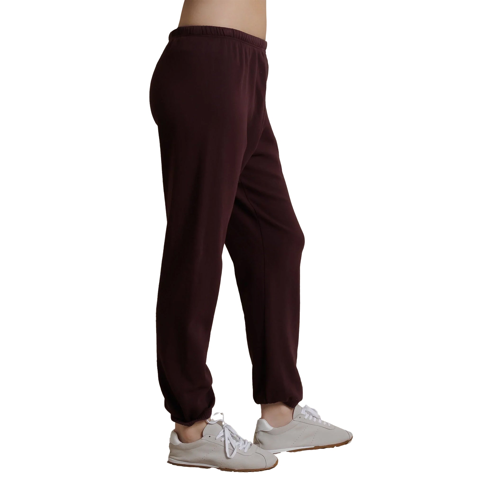 A person shown from the waist down wearing dark burgundy jogger sweatpants and white sneakers, photographed against a plain white background.