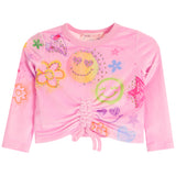 A pink long-sleeve crop top for kids, featuring a front drawstring tie and an all-over colorful graphic print with smiley faces, flowers, stars, and hearts. 