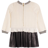 A girls' cable-knit zip-front sweater jacket in cream with black and white striped trim on the collar, cuffs, and hem, paired with a black faux-leather pleated skirt, shown on a plain white background.
