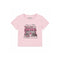 A light pink short-sleeve t-shirt for kids by Katie J, featuring a graphic print of a Parisian-style boutique with red and white striped awning, pink flowers, and a heart on the front.