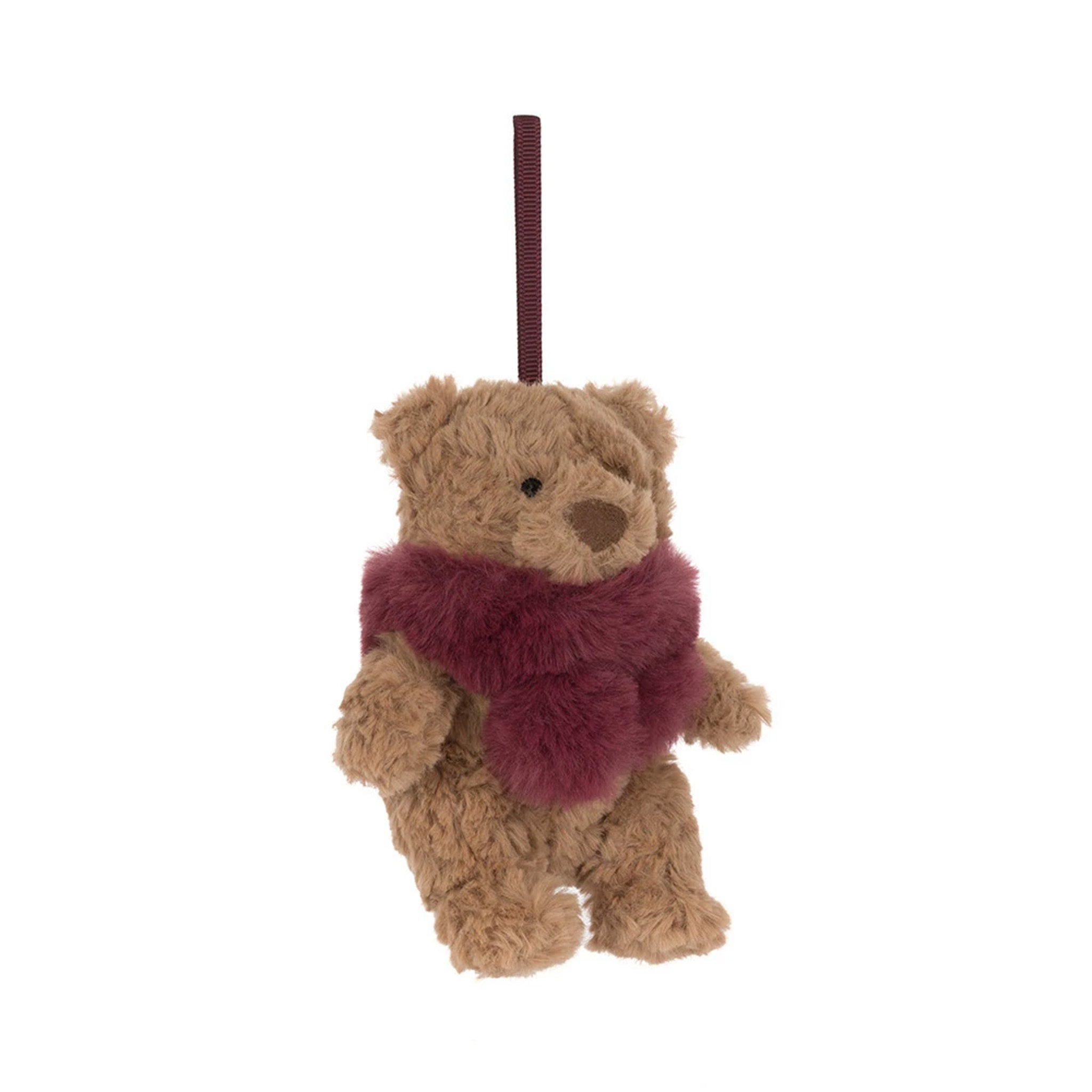 A small plush teddy bear ornament hanging from a dark red ribbon. The teddy bear is light brown with a fuzzy dark red scarf.