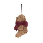 A small plush teddy bear ornament or hanging decoration in tan with a fuzzy burgundy scarf, suspended by a thin dark string against a plain white background.