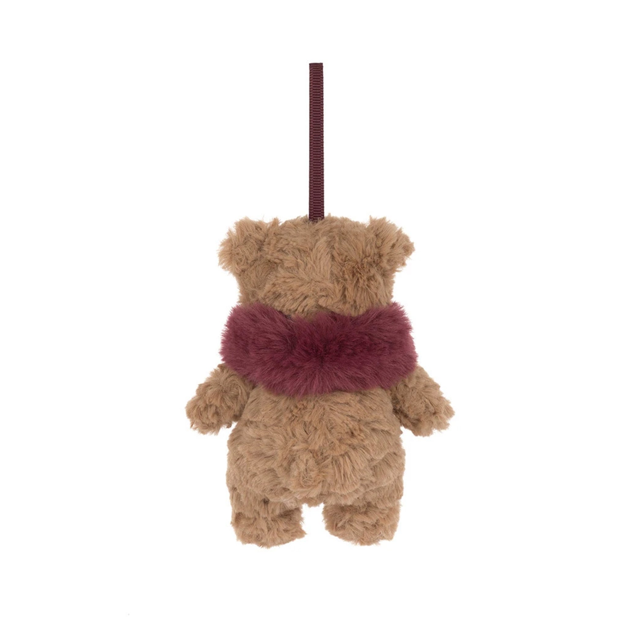 A small plush teddy bear ornament or hanging decoration in warm tan with a fuzzy burgundy scarf and a matching hanging loop, shown on a plain white background.