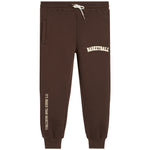 Dark brown sweatpants with white drawstrings, featuring 'BASKETBALL' printed in white on the upper right thigh and 'IT'S BIGGER THAN BASKETBALL' printed vertically in white on the lower left leg.