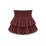 A tiered ruffle mini skirt in a dusty rose-brown color with a small pink floral pattern, featuring a smocked elastic waistband, shown against a plain white background.