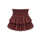 A tiered ruffle mini skirt in a dusty rose-brown color with a small pink floral pattern, featuring a smocked elastic waistband, shown against a plain white background.