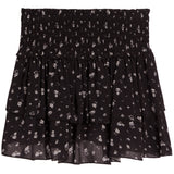 A black tiered ruffle mini skirt with a small white floral pattern, featuring a smocked elastic waistband.