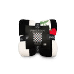 A folded Living Royal Super Cozy Blanket with a black and white striped pattern, a red apple with green leaves, and a black paper label in the center.