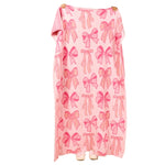 A pink blanket with a repeating bow pattern, hanging against a plain white background.