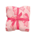 A folded pink plush blanket with a darker pink bow pattern, wrapped in a bright pink ribbon tied into a bow, on a plain white background.